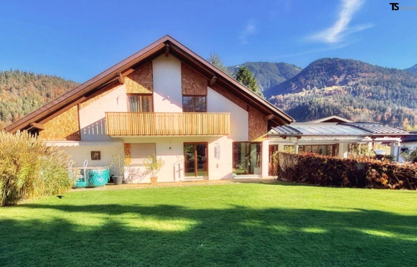 Traditionelles Chalet mit großem Garten, Balkon und Wintergarten, umgeben von einer malerischen Berglandschaft.