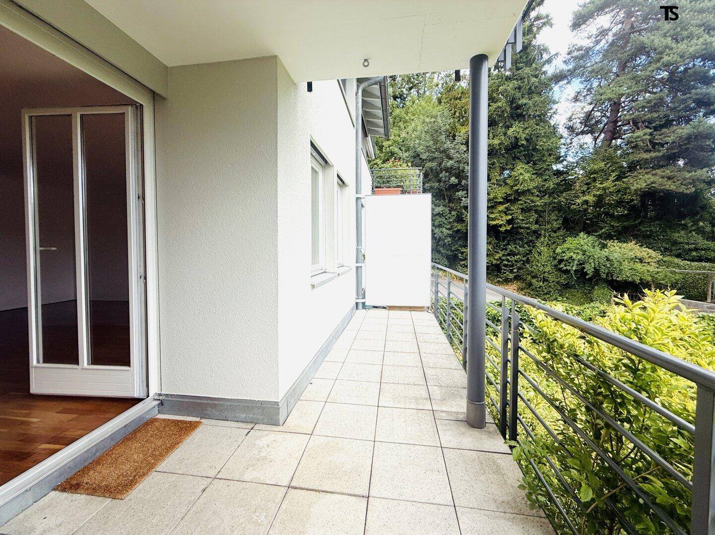 Geräumige Terrasse mit Fliesenboden und Blick ins Grüne, ideal für entspannte Stunden im Freien.