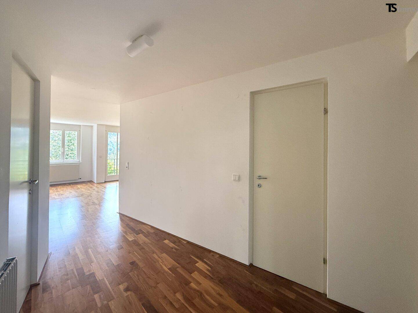 Heller Flur mit Parkettboden, der zu den verschiedenen Räumen der Wohnung führt.