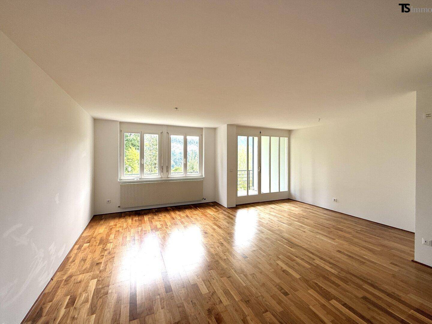 Geräumiges Wohnzimmer mit viel Tageslicht und Zugang zu einem Außenbereich, ideal für Entspannung.