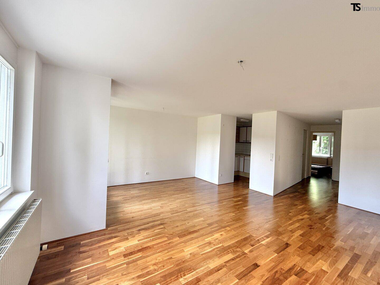 Helles Wohnzimmer mit elegantem Parkettboden und großen Fenstern, bereit zur individuellen Gestaltung.