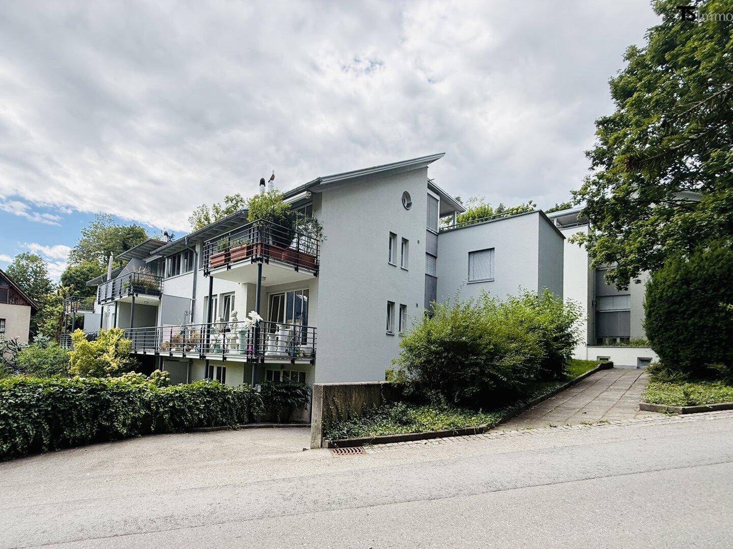 Modernes Mehrfamilienhaus mit mehreren Balkonen und ansprechender Architektur in grüner Umgebung.