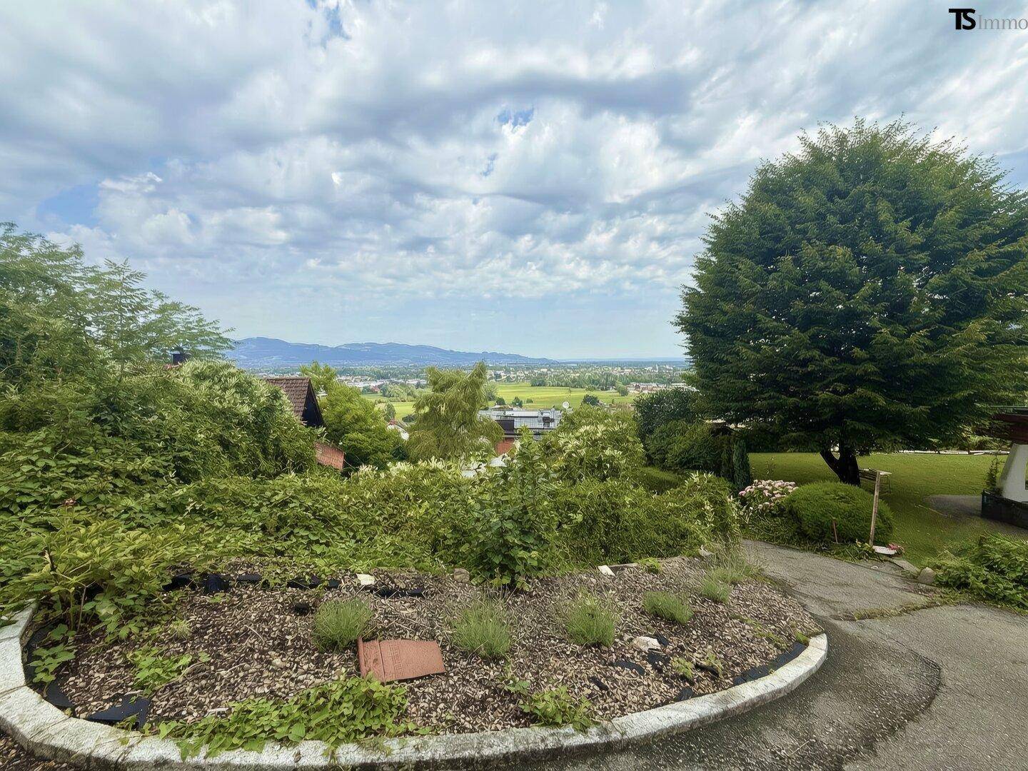 Gepflegter Gartenbereich mit Pflanzen und weitem Blick über die Landschaft und die Stadt.