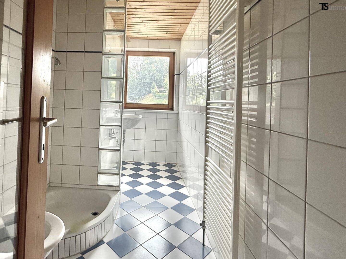 Helles Badezimmer mit karierten Fliesen, Dusche und Fenster für natürliches Tageslicht.