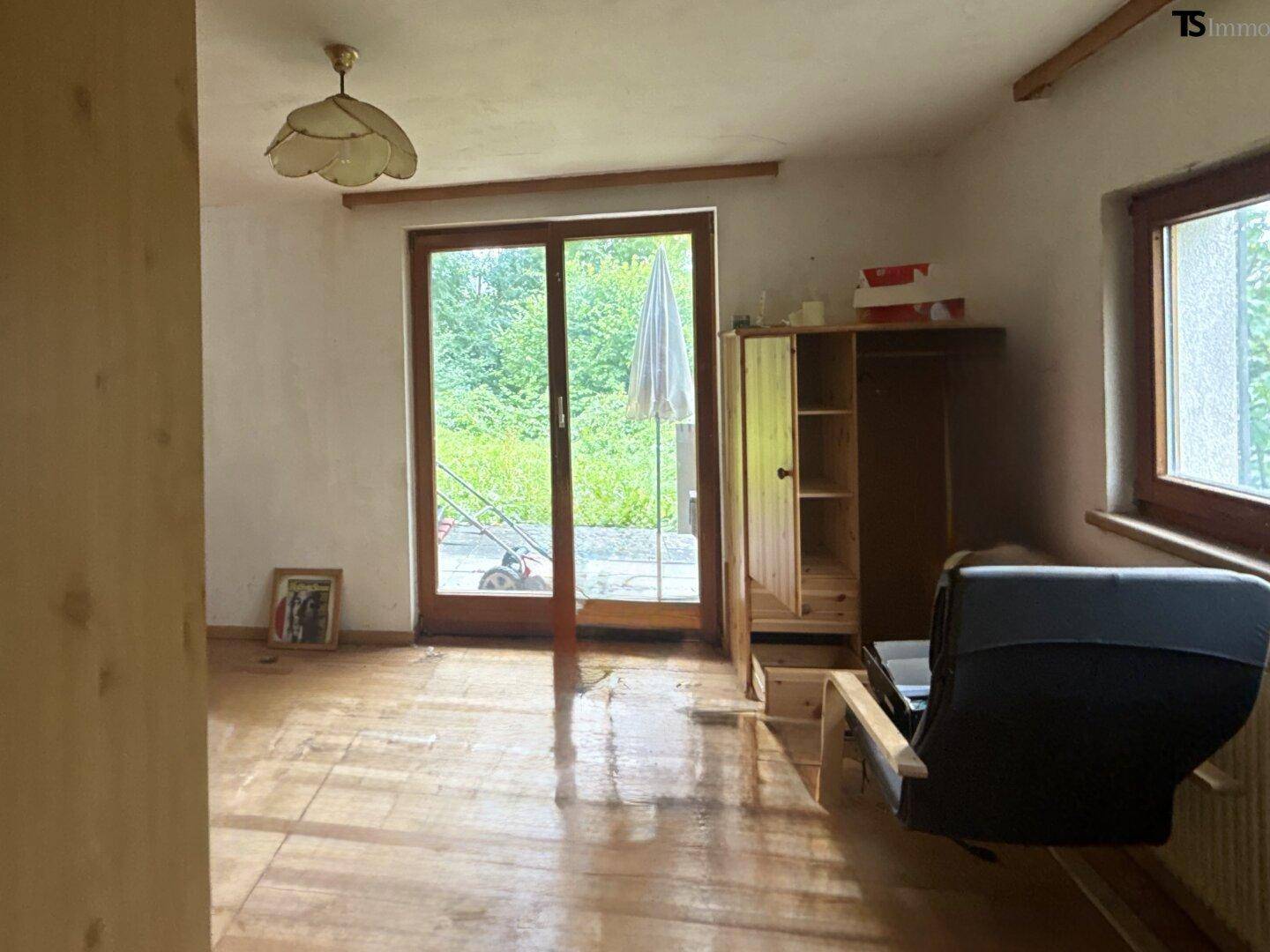 Wohnzimmer mit Holzboden und direktem Zugang zur Terrasse und dem Gartenbereich.