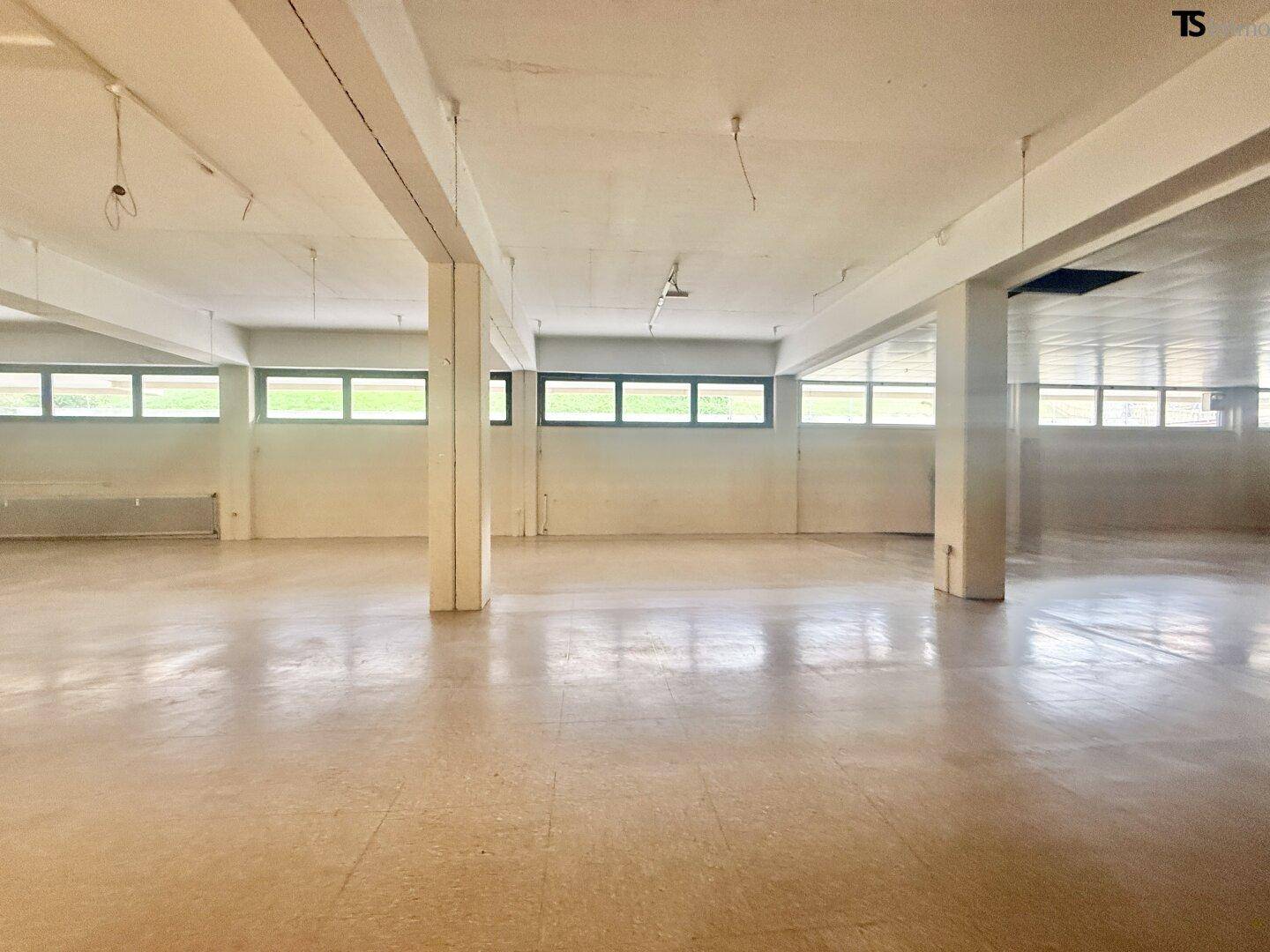 Großer, leerer Gewerberaum mit vielen Fenstern und Säulen, bereit für den Ausbau.