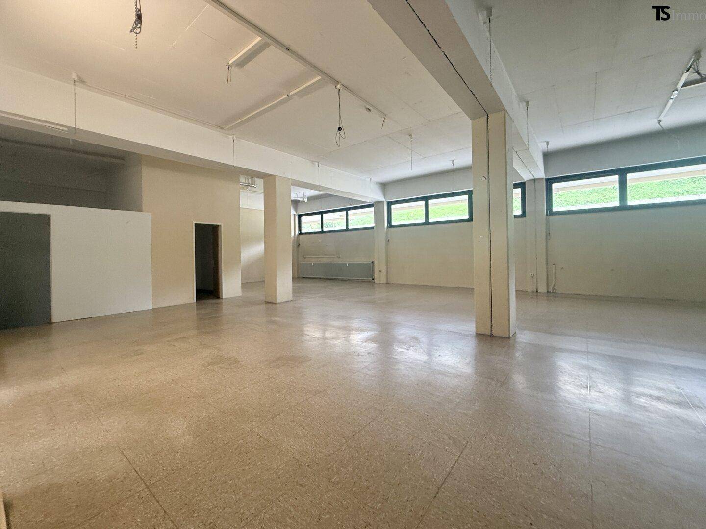 Weitläufiger Gewerberaum mit hohen Decken und zahlreichen Fenstern, ideal für verschiedene Geschäftsnutzungen.