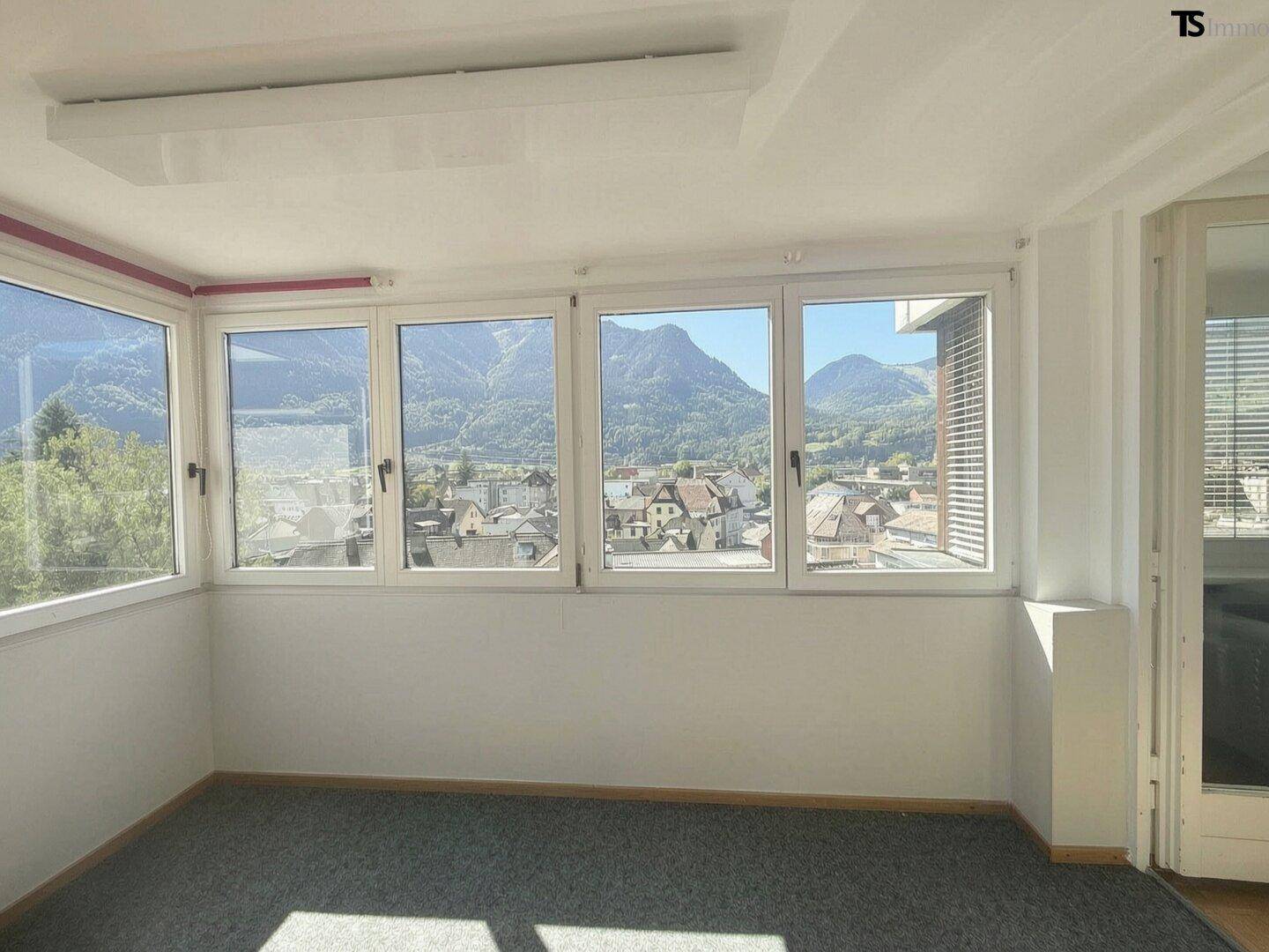 Heller Wintergarten mit Panoramablick auf die Berge und die Stadt, ideal zum Entspannen.
