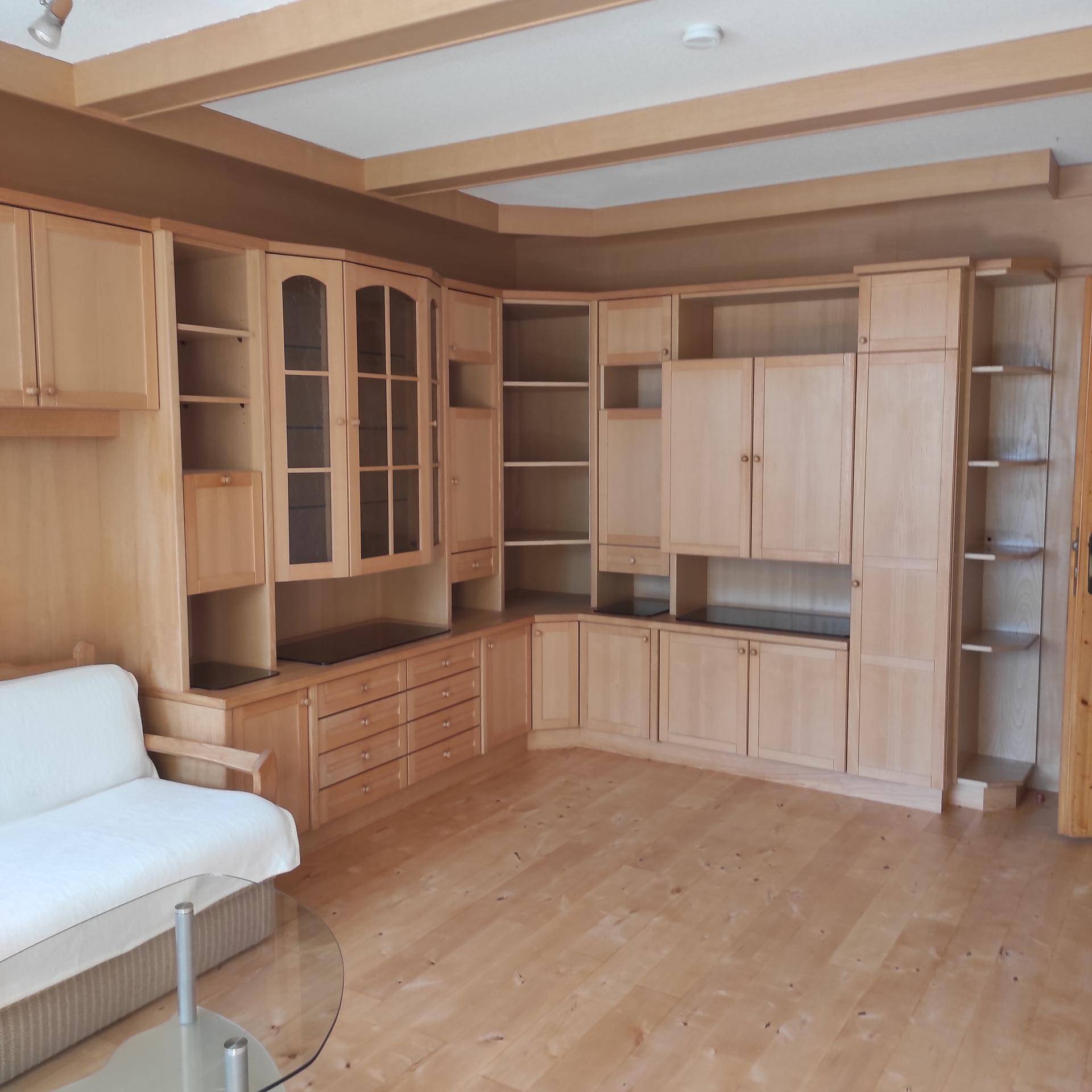 Geräumiges Wohnzimmer mit umfangreichen Einbauschränken aus hellem Holz und einem bequemen Sofa.