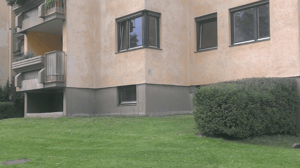 Fassade eines Wohngebäudes mit Balkonen und einem gepflegten Rasenbereich im Vordergrund.