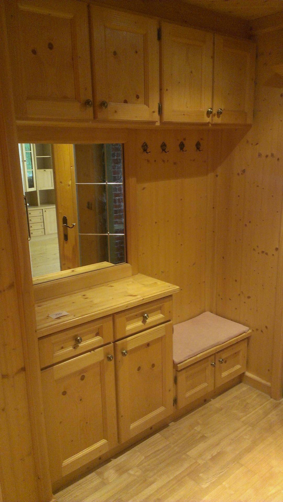 Eingangsbereich mit rustikalen Holzvertäfelungen, integrierten Schränken, Spiegel und einer Sitzbank.