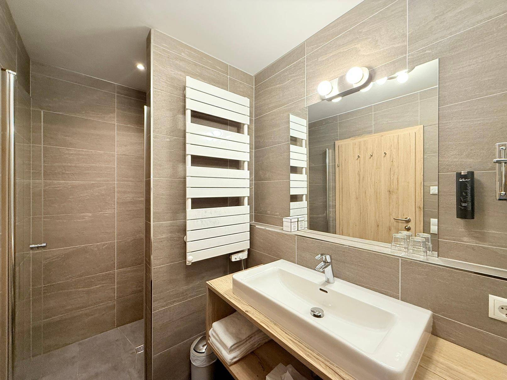 Elegantes Badezimmer mit begehbarer Dusche, modernem Waschtisch und praktischem Handtuchheizkörper.