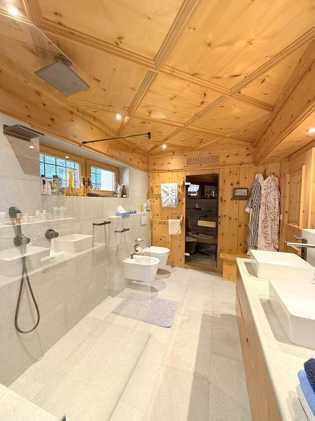 Geräumiges Badezimmer mit Bidet, Dusche und Holzdecke, ausgestattet mit modernen Armaturen.
