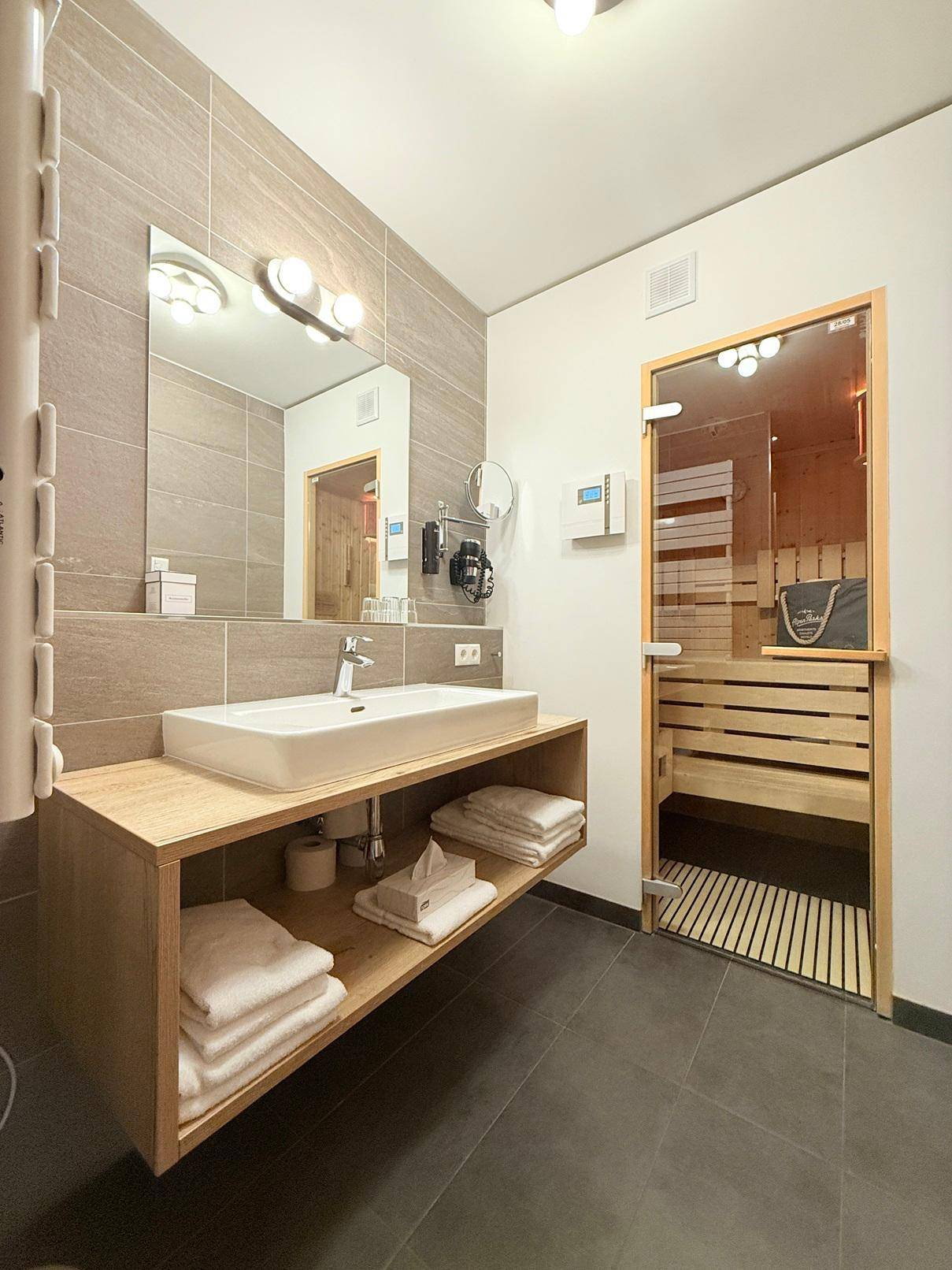 Modernes Badezimmer mit stilvollem Waschtisch, großem Spiegel und einer integrierten Sauna für Entspannung.