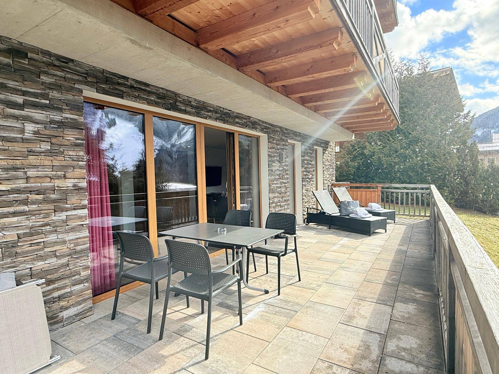 Großzügige Terrasse mit Essbereich im Freien, Liegestühlen und einem Whirlpool mit Bergblick.