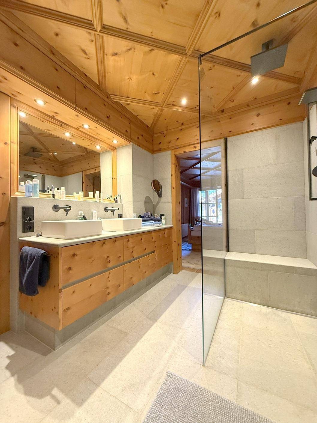 Modernes Badezimmer mit Doppelwaschbecken, begehbarer Dusche und Holzdecke.