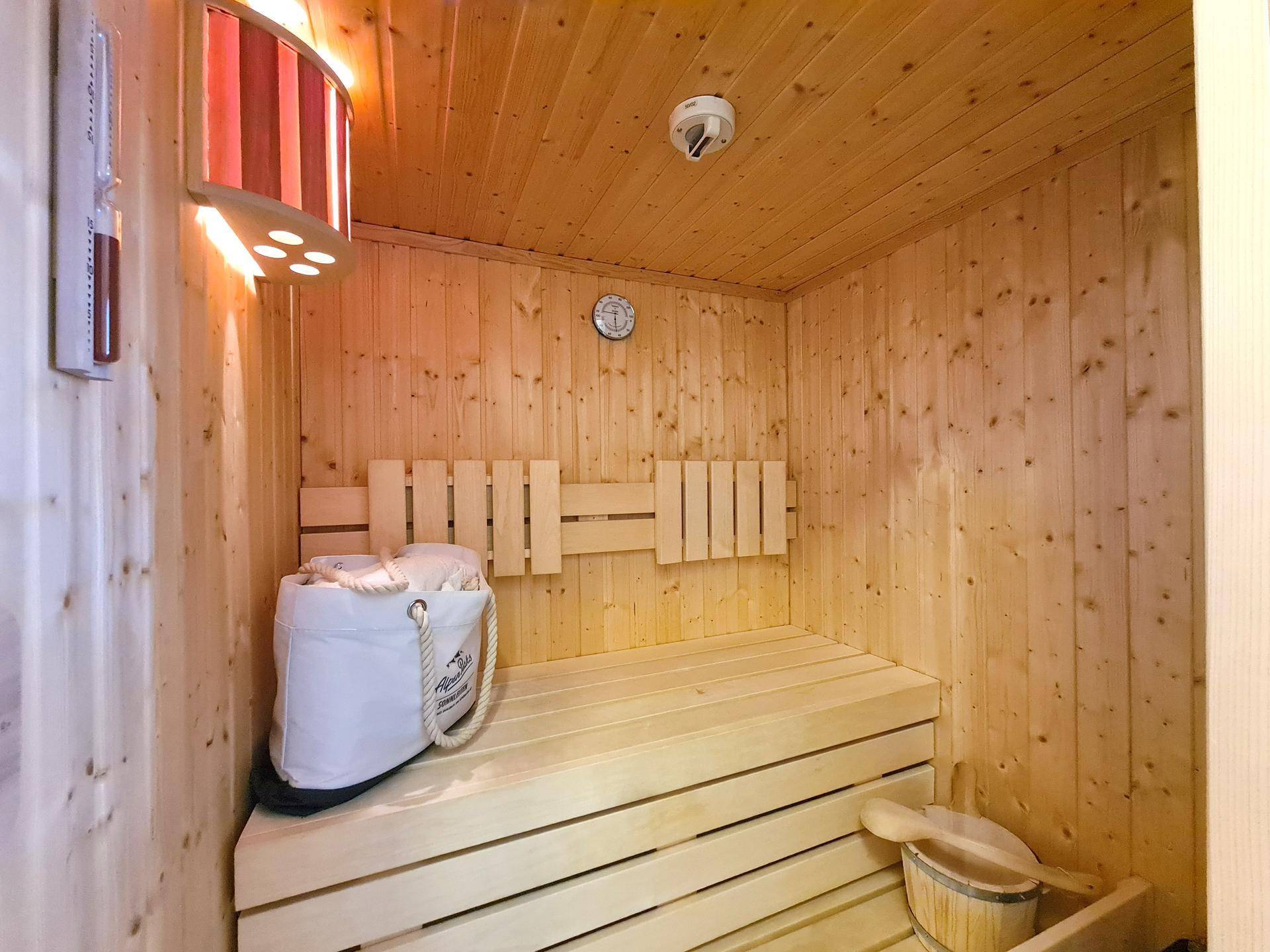 Innenansicht einer holzverkleideten Sauna mit Bänken und Heizofen.