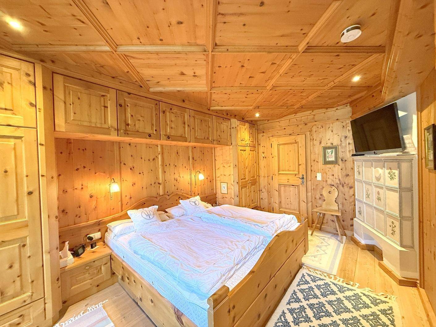 Schlafzimmer im alpinen Stil mit Holzwänden, Holzboden und Einbauschränken.