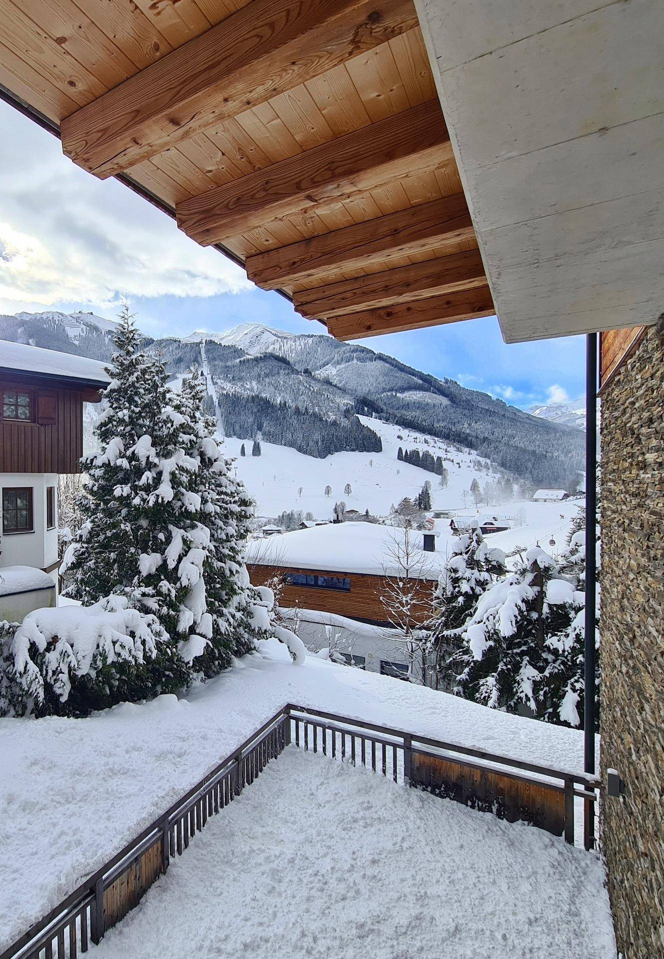 Winterlicher Balkon mit Holzbalken und weitem Blick auf die verschneite Landschaft.