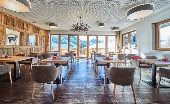 Elegantes Restaurant mit Holzwänden, modernen Tischen und Stühlen sowie Panoramablick auf die Berge.