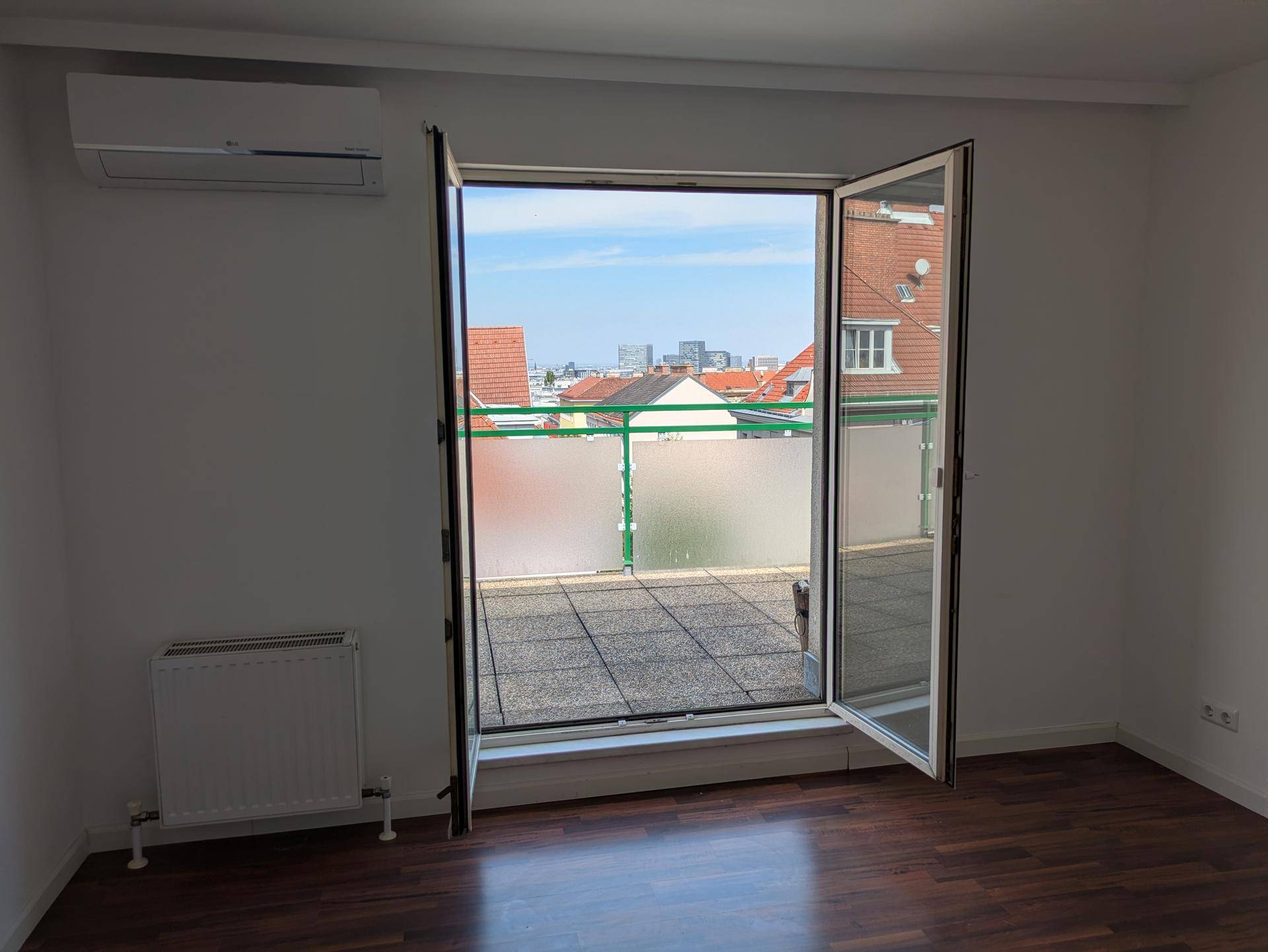 Große Terrassentüren öffnen sich zu einem Außenbereich und bieten einen weiten Blick über die Stadt.