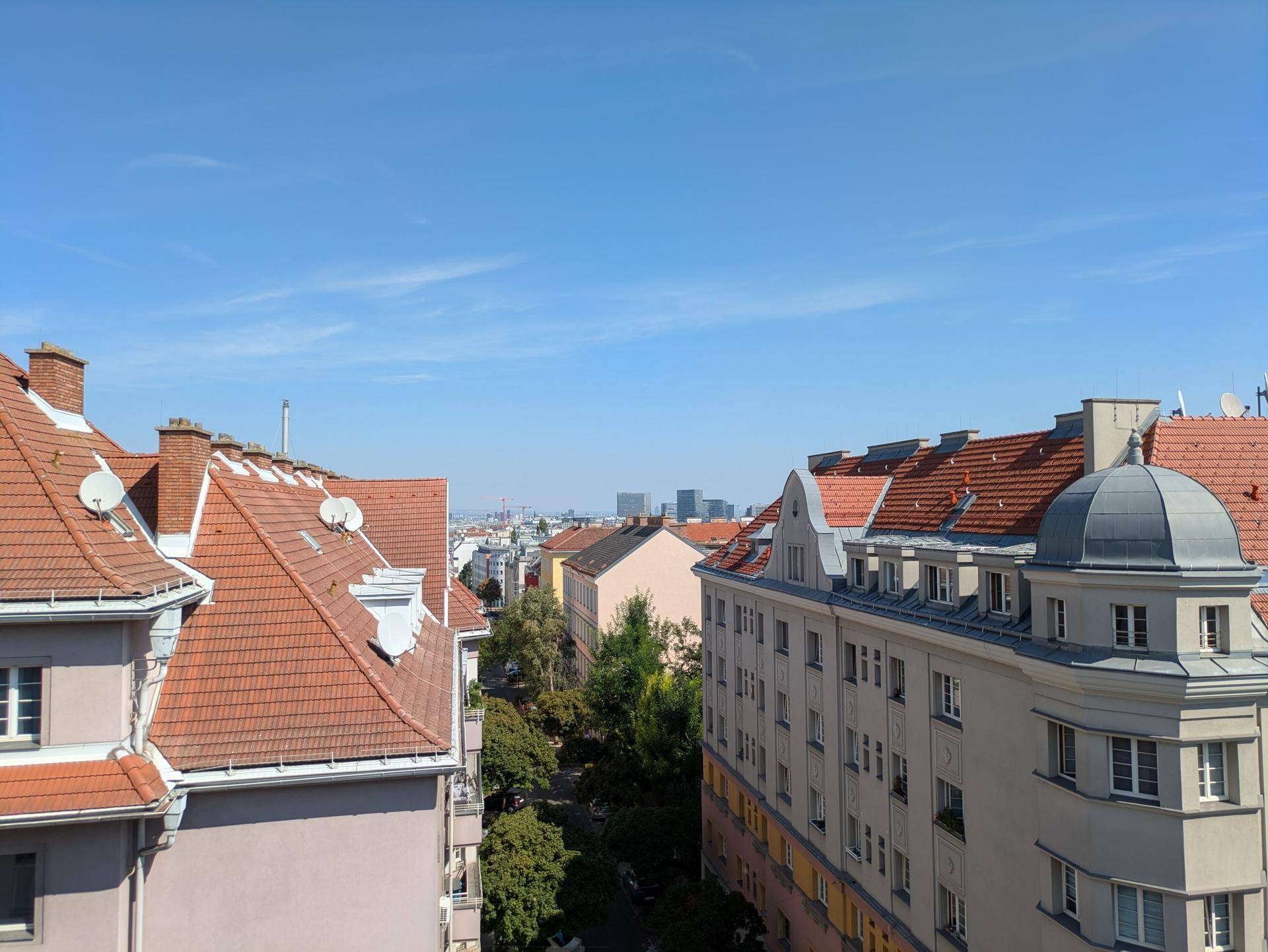 Panoramablick über die Dächer der Stadt mit traditionellen Gebäuden und blauem Himmel.