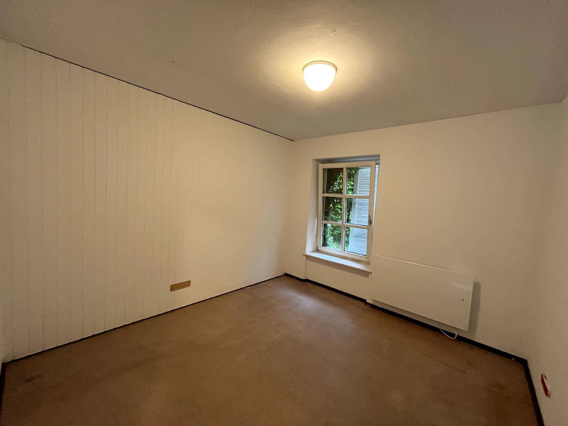 Helles Zimmer mit einem Fenster und Heizkörper, ideal als Schlaf- oder Arbeitszimmer.