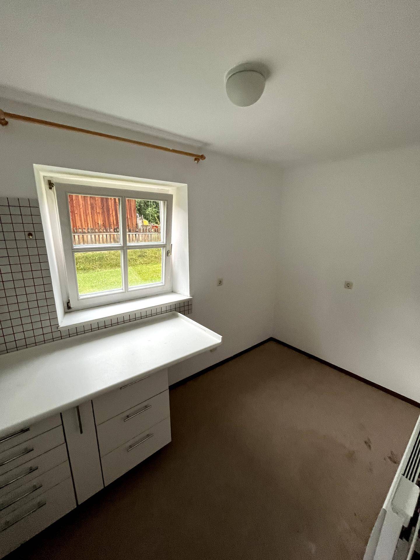 Kleiner Raum mit Arbeitsplatte und Fenster, ideal als Hauswirtschaftsraum oder kleine Küche.