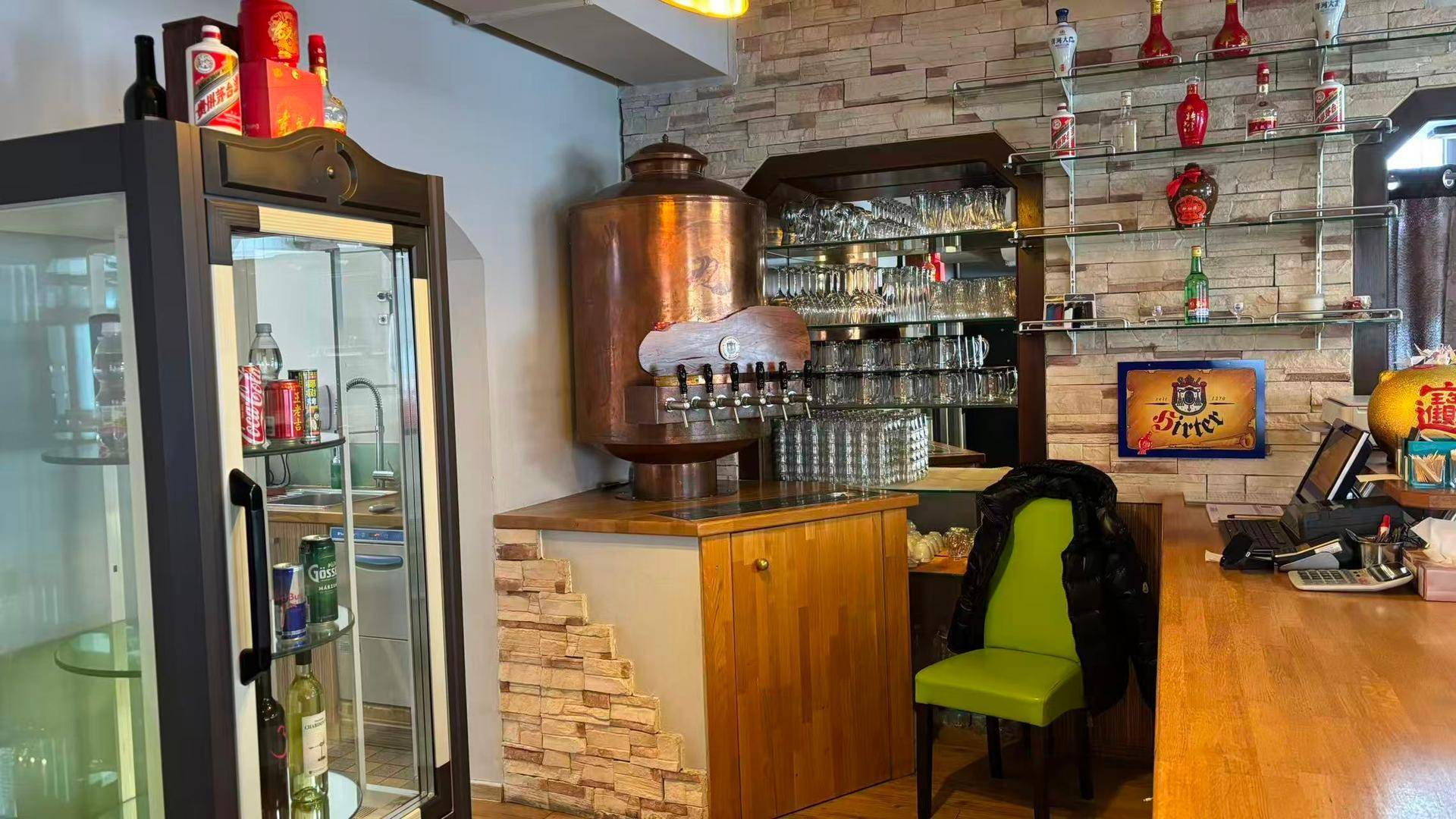 Gastronomischer Barbereich mit Zapfanlage, Flaschenregalen und rustikaler Steinwandverkleidung.