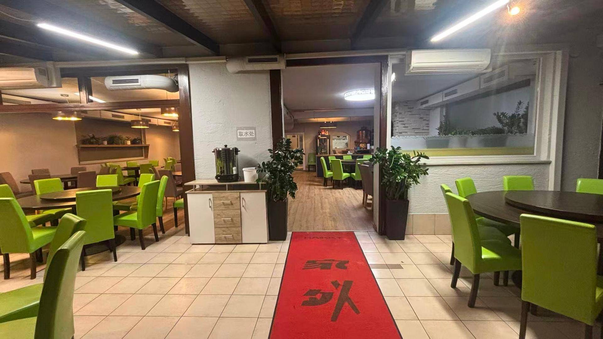 Restaurant-Innenraum mit rotem Teppich, gefliestem Boden und verschiedenen Sitzbereichen.
