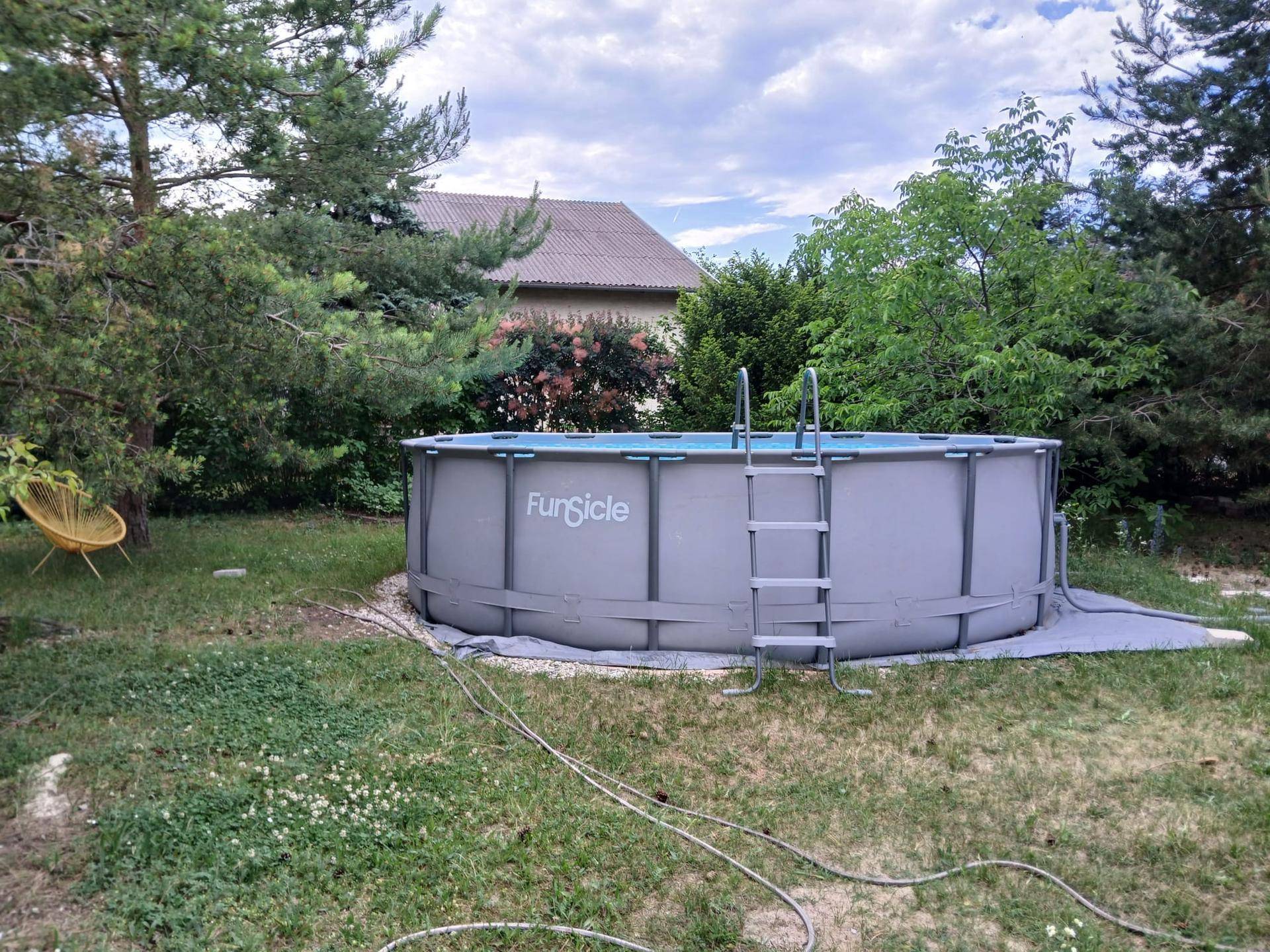 Großer Garten mit einem aufgestellten Pool und altem Baumbestand, perfekt für sommerliche Erfrischung.