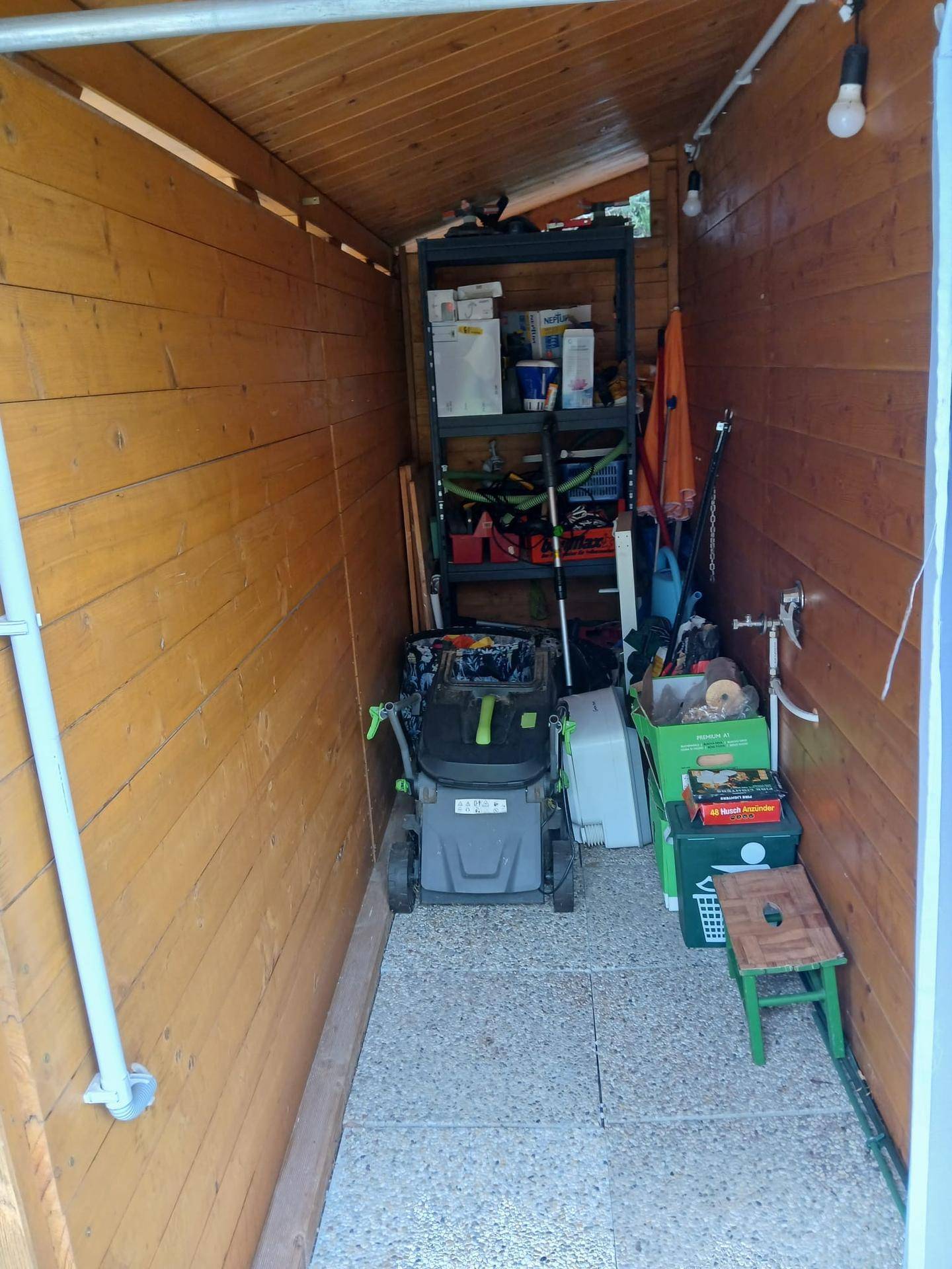 Schmaler Holzschuppen, genutzt als Lagerraum für Gartengeräte und diverse Haushaltsgegenstände.