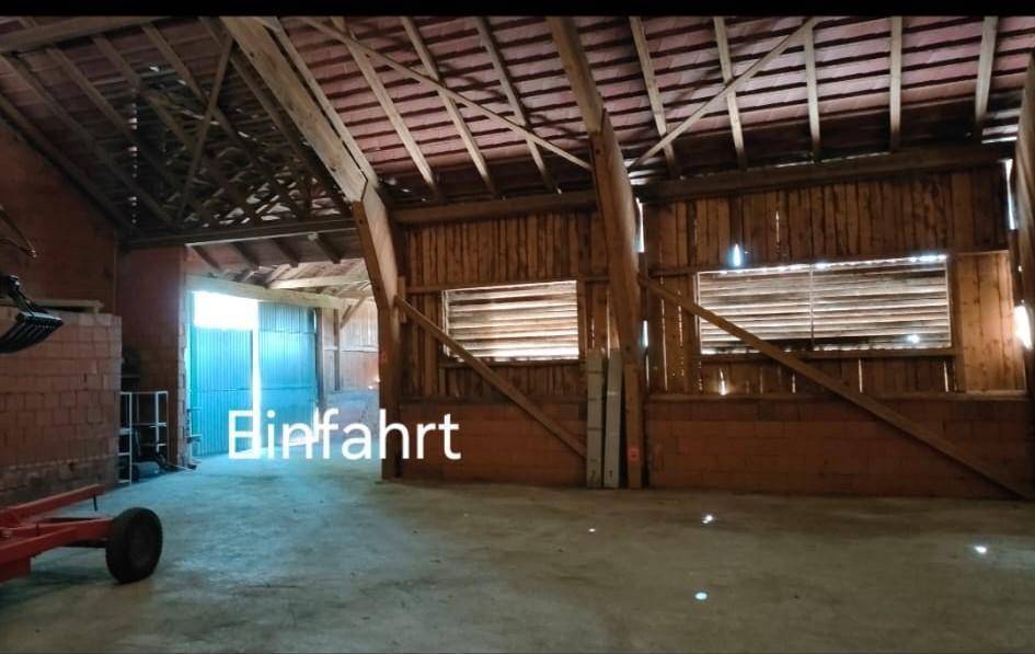 Blick in den großen Innenraum der Scheune mit Holzwänden und einem Eingangsbereich.