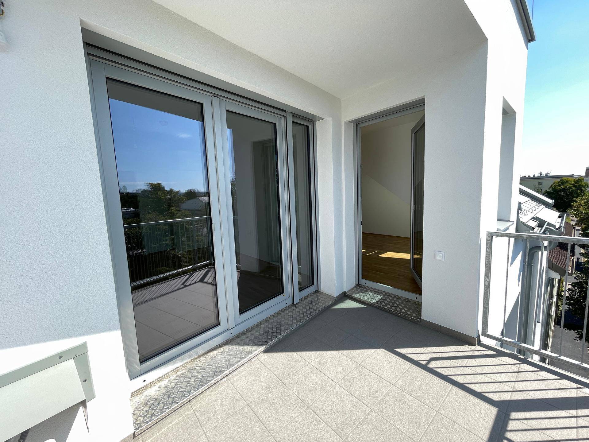 Geräumiger Balkon mit Fliesenboden und Zugang zu Innenräumen, bietet viel Sonnenlicht.