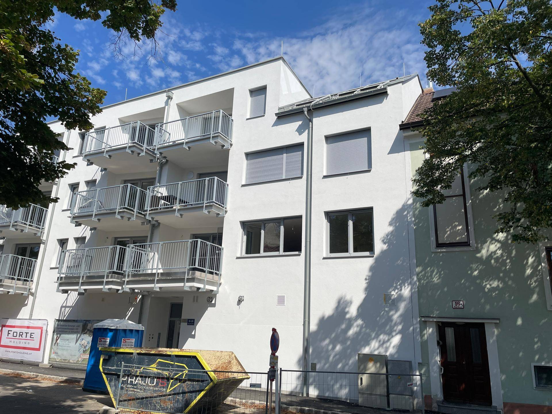 Neubau mit moderner Architektur, Balkonen und Baustellenelementen im Vordergrund.