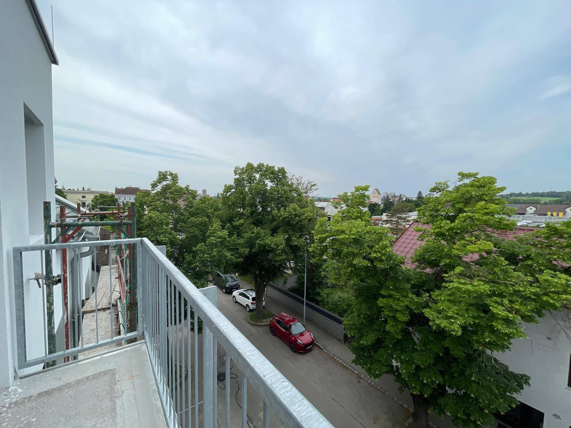 Balkon mit Blick auf eine von Bäumen gesäumte Straße und die umliegende Nachbarschaft.