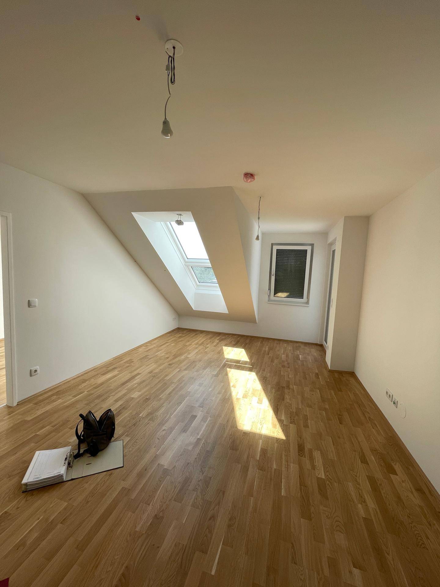 Geräumiger Wohnbereich mit Parkettboden, Dachschrägen und viel natürlichem Licht.
