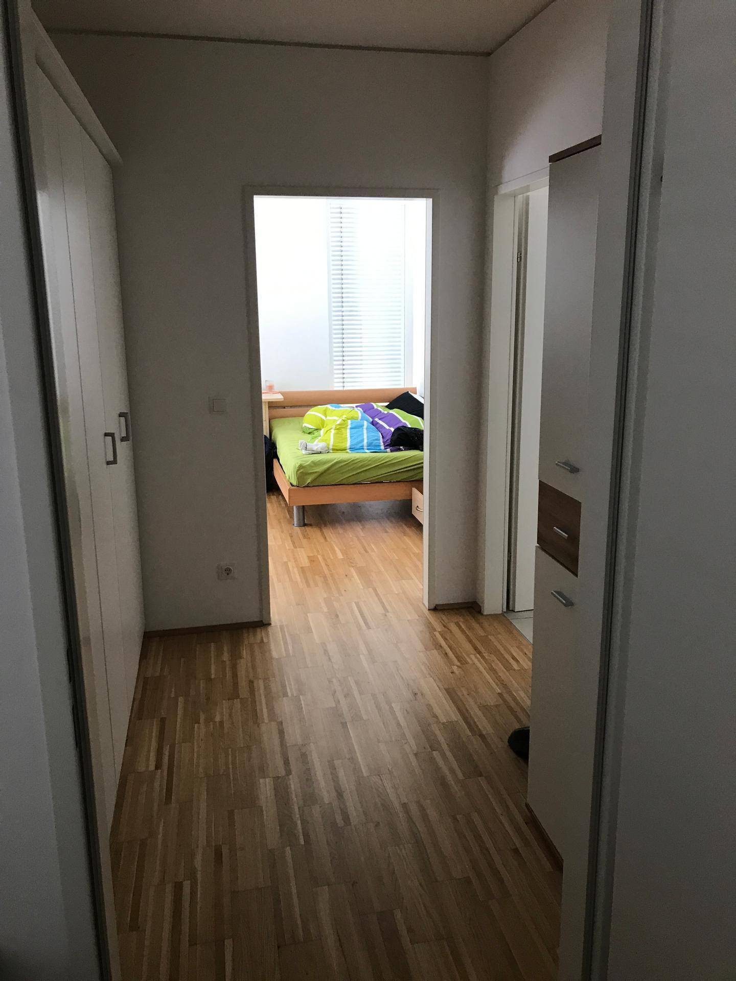 Heller Flur mit Holzboden und Zugang zu weiteren Zimmern.