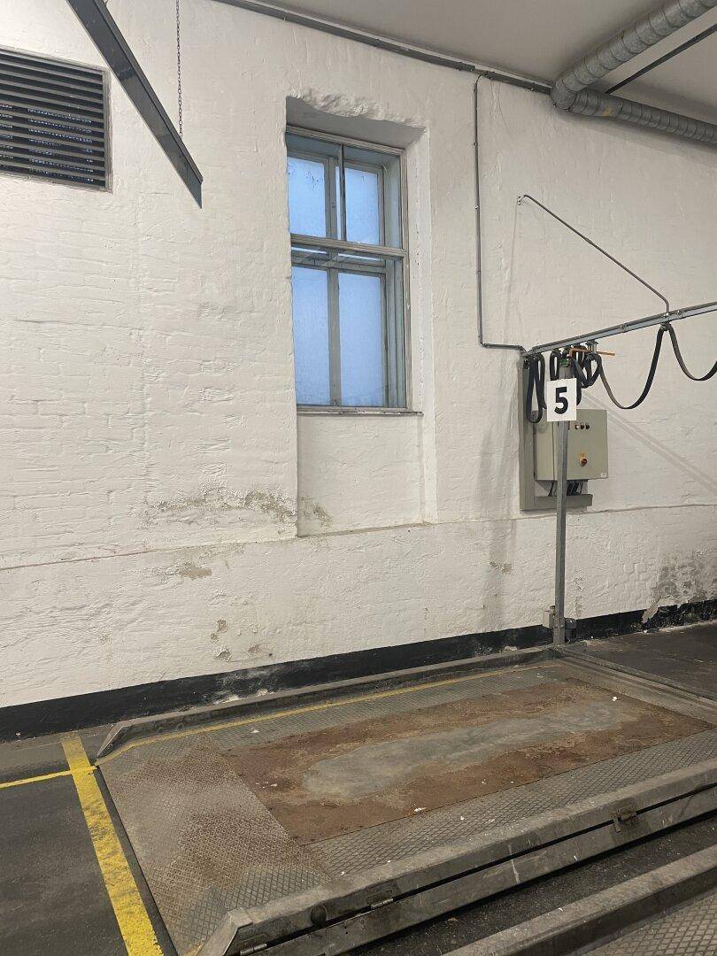 Tiefgarage mit einem Doppelparker und einem kleinen Fenster in der weiß gestrichenen Ziegelwand.