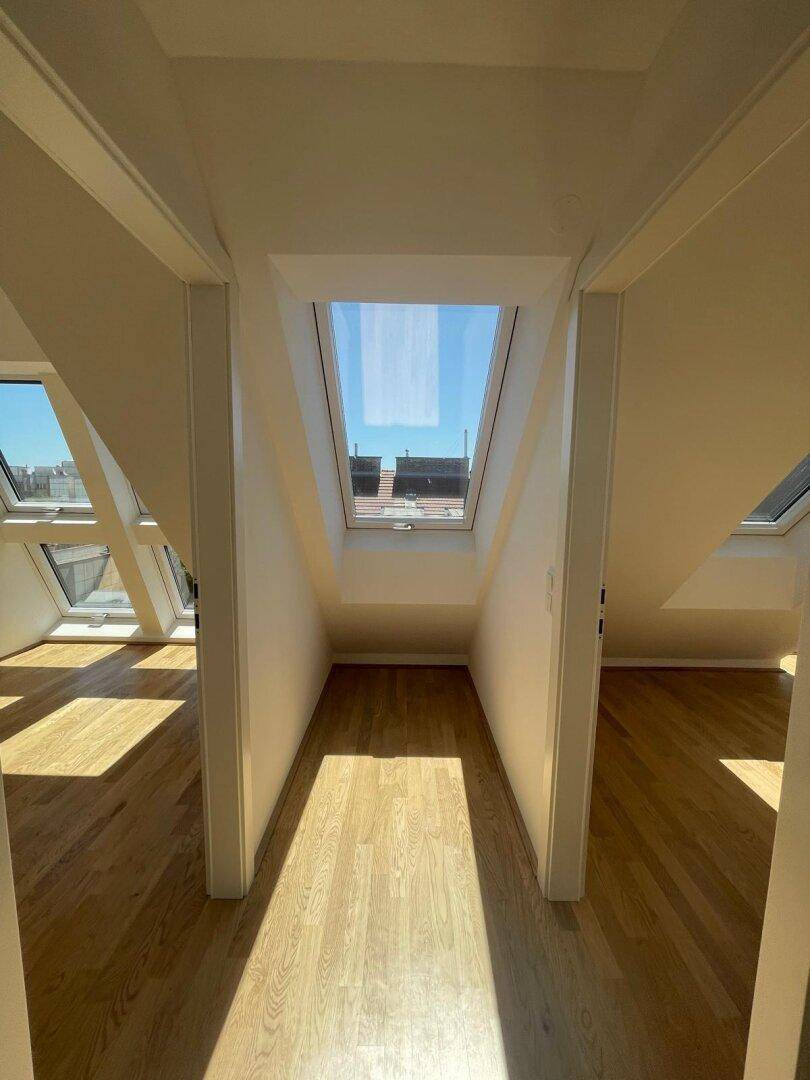 Heller Flur im Dachgeschoss mit Holzboden und einem Oberlicht, das den Bereich natürlich beleuchtet.
