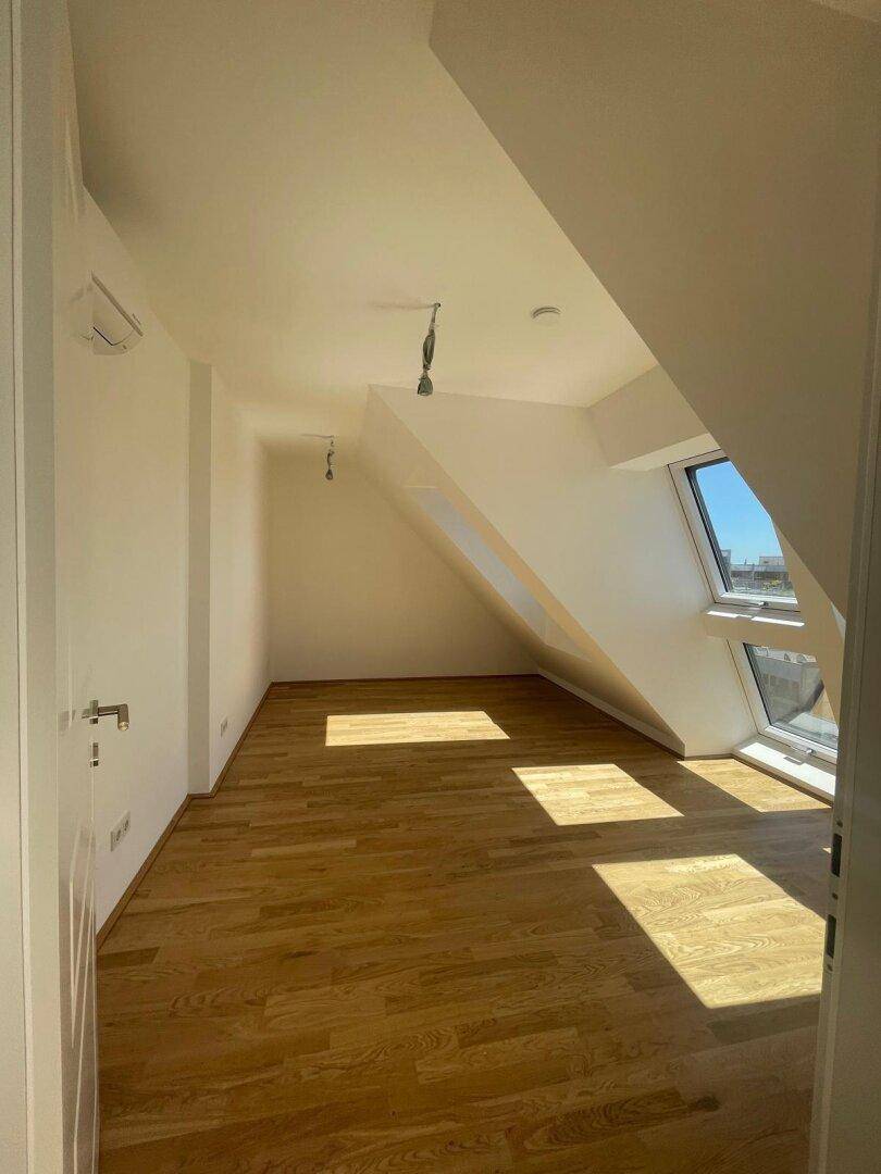 Geräumiges Dachgeschosszimmer mit Holzboden und schrägen Wänden, ideal für individuelle Gestaltungsmöglichkeiten.