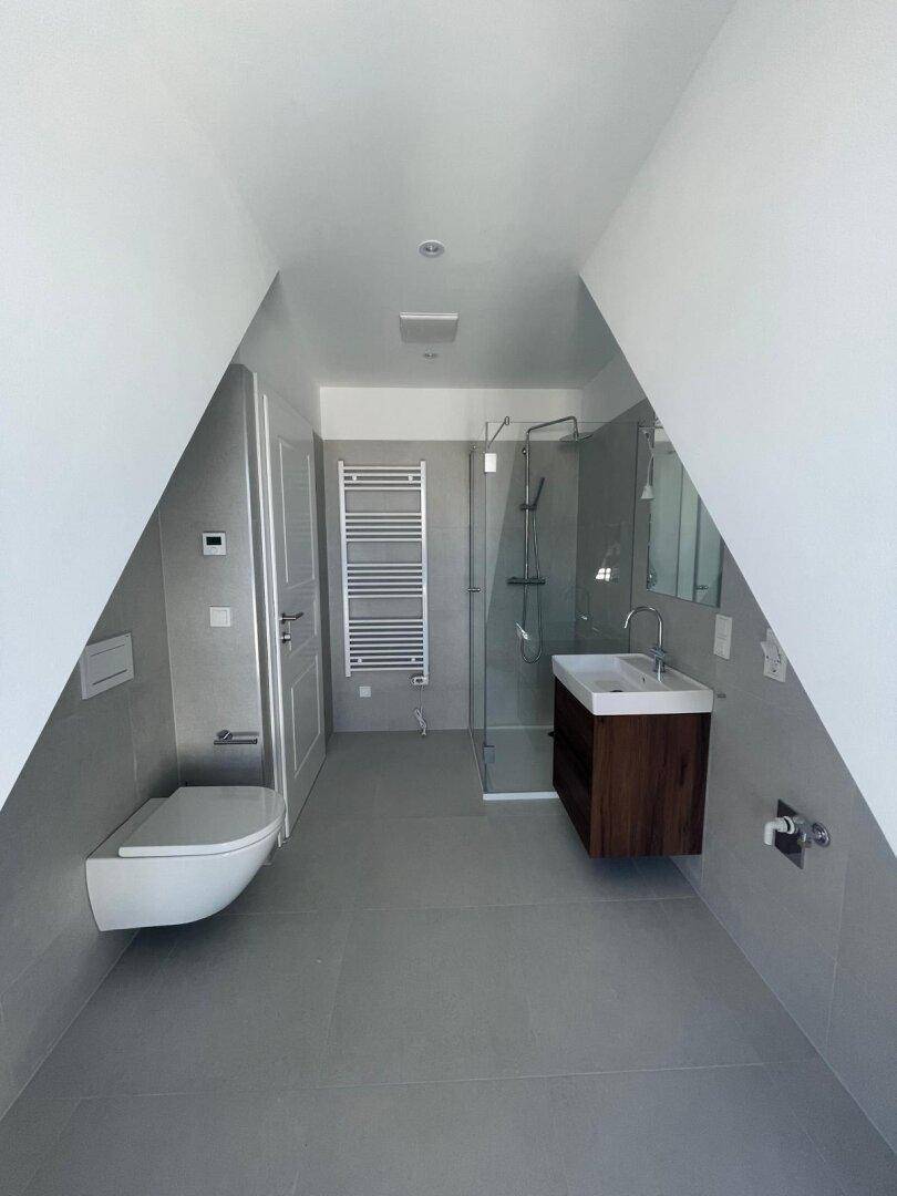 Modernes Badezimmer im Dachgeschoss mit Dusche, Wand-WC und beheiztem Handtuchhalter.