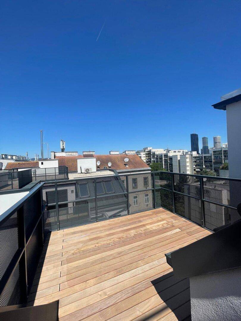 Geräumige Dachterrasse mit Holzboden und Blick über die Stadt, ideal für Entspannung im Freien.