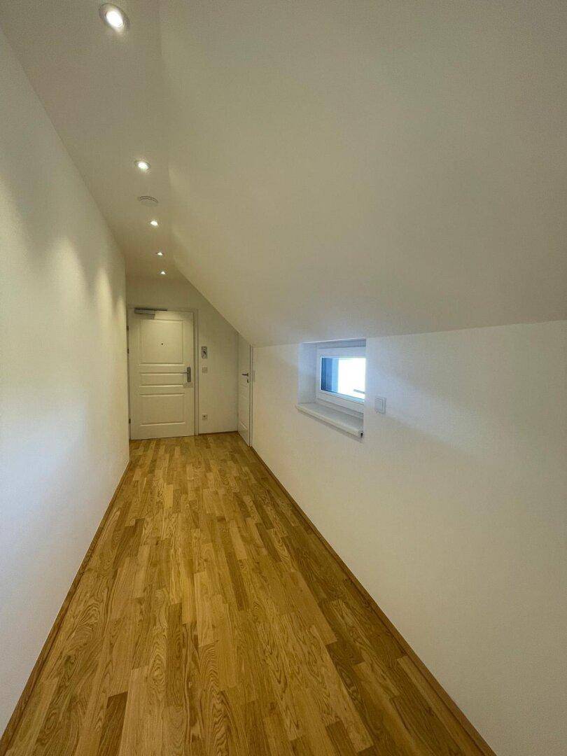 Langer, heller Flur mit Holzboden und Einbaustrahlern, der zu den verschiedenen Räumen führt.