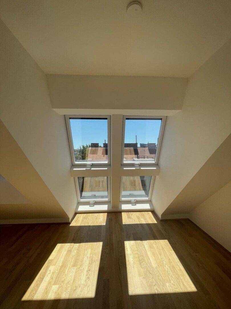 Große Dachfenster bieten einen weiten Blick und lassen viel Tageslicht in diesen hellen Dachgeschossraum.