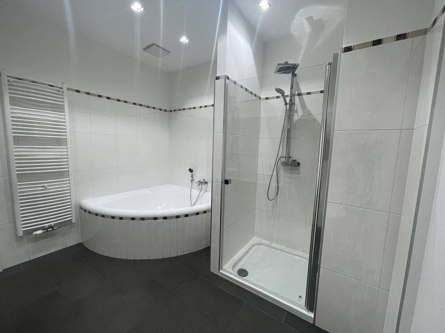 Modernes Badezimmer mit Eckbadewanne, Duschkabine und beheiztem Handtuchhalter.