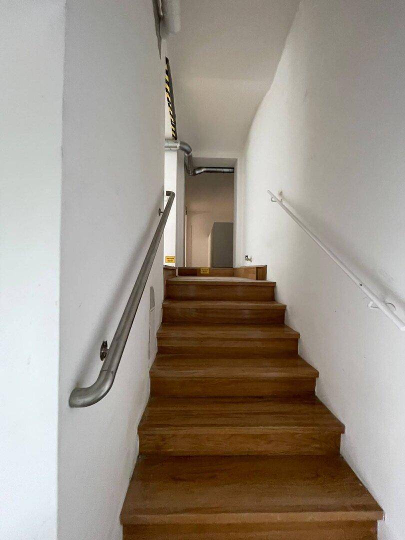 Holztreppe mit Handläufen, die zu einem oberen Bereich führt und gut erhalten ist.