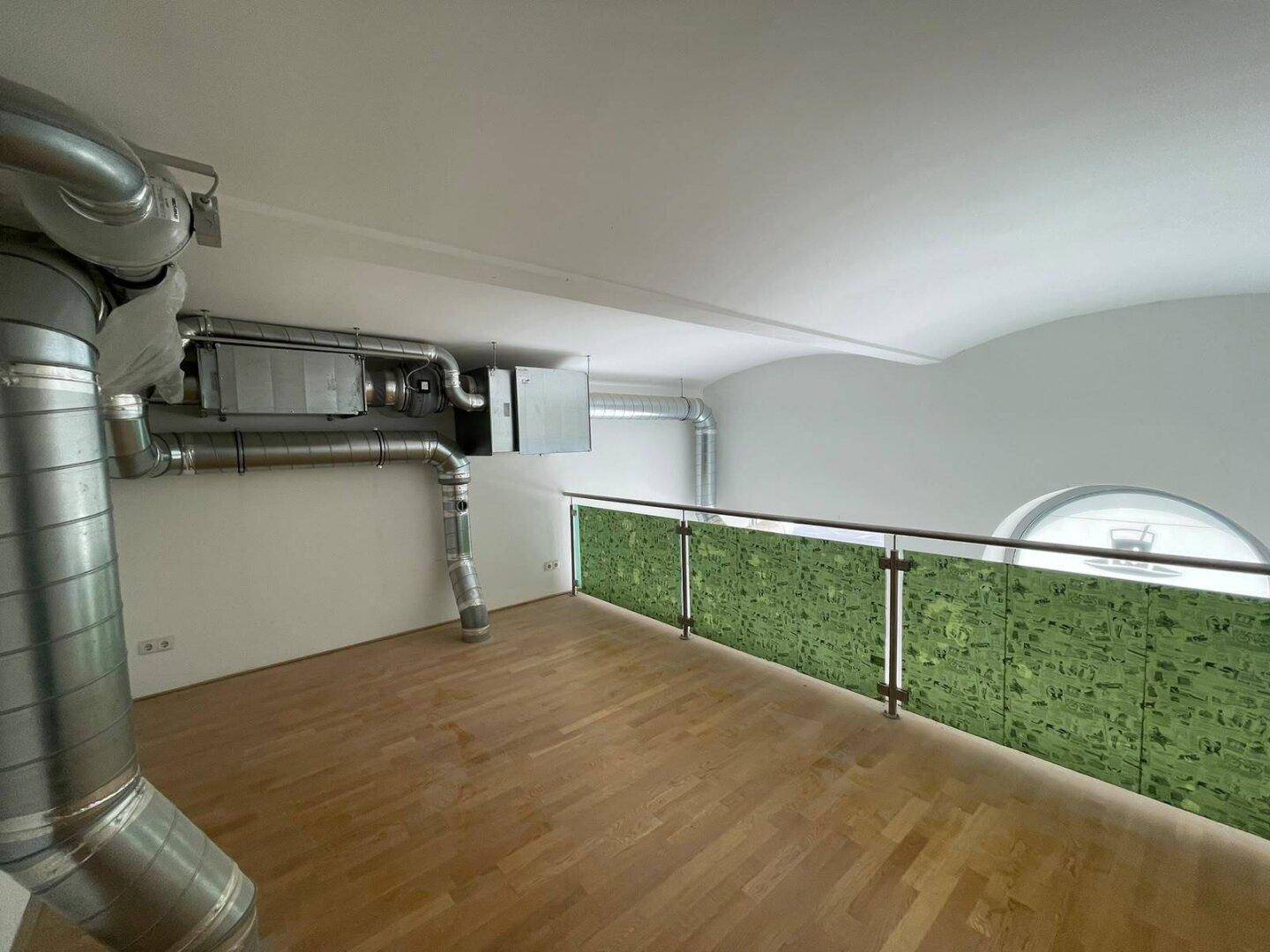 Obere Ebene eines Ladenlokals mit Holzboden, grüner Brüstung und einer gewölbten Decke.