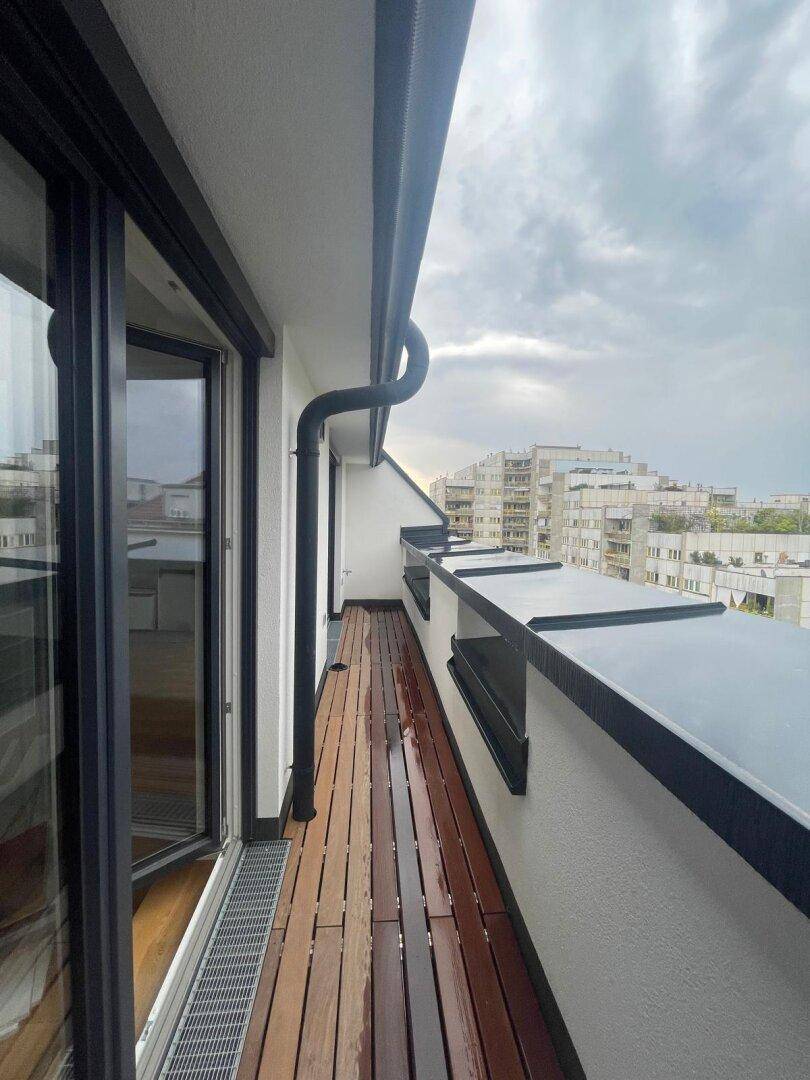 Schmaler Holzbalkon entlang der Fassade mit Blick auf die umliegenden Gebäude.