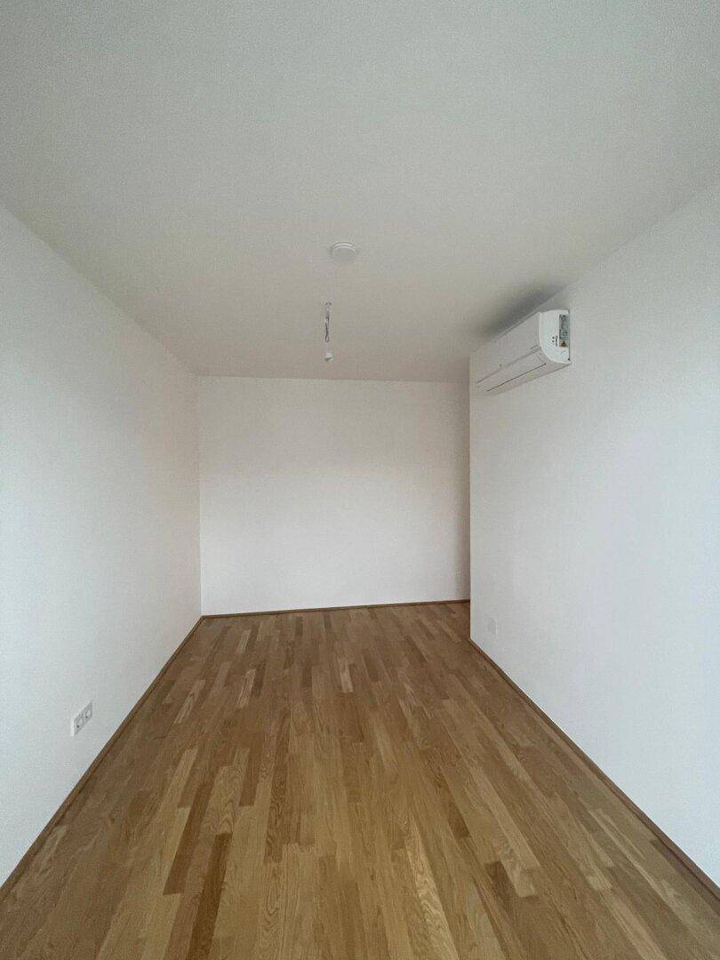 Heller Raum mit Holzboden und Klimaanlage, bereit für individuelle Gestaltung.